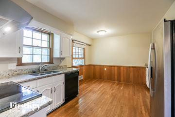 Overland Park house for rent - A kitchen with wooden floors and white cabinets.