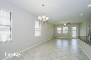 Ruskin house for rent - A spacious room with a chandelier and a fan.