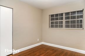 Cutler Bay house for rent - a bedroom with a window and wooden floors and a white door