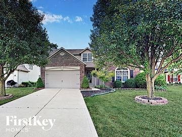 Indianapolis house for rent - a home with a white garage door and a lawn and trees