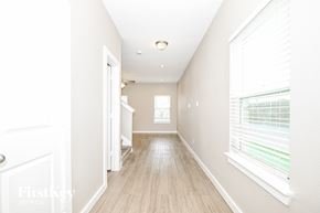 Dallas house for rent - A long hallway with a white door on the left and a window with blinds on the right.