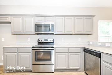 Dallas house for rent - A kitchen with a stove top oven and microwave above it.