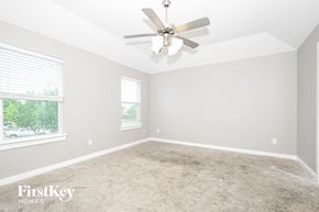 Dallas house for rent - A spacious room with a ceiling fan and two windows.