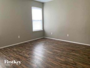Dallas house for rent - an empty living room with wood floors and a window