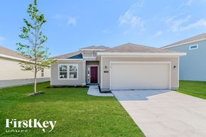 Jacksonville house for rent - A house with a red door and a garage door is shown with a tree in front of it.