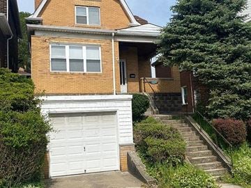Pittsburgh house for rent - A house with a white garage door and a brick facade.