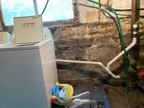 Buffalo apartment for rent - A dirty wall with a white pipe and a green hose.