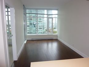 Vancouver apartment for rent - A room with a large window and wooden floors.