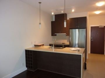 Vancouver apartment for rent - A kitchen with a refrigerator, sink, and cabinets.