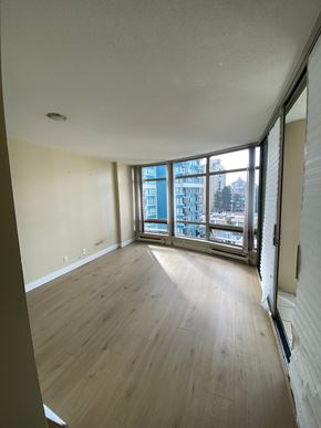 Vancouver apartment for rent - A room with wooden floors and a large window overlooking a city.
