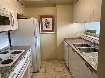 Vancouver apartment for rent - A kitchen with a white refrigerator, white cabinets, and a granite countertop.