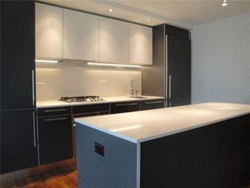 Vancouver apartment for rent - A modern kitchen with black cabinets and a white countertop.