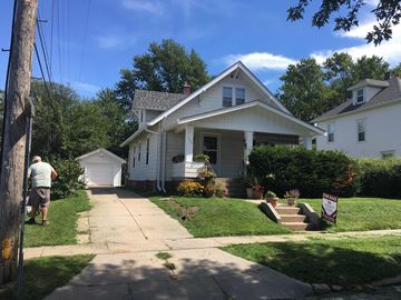 Omaha apartment for rent - A man is walking on the sidewalk in front of a white house.