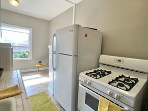 Alameda apartment for rent - A white refrigerator and stove in a kitchen with a yellow towel hanging on the stove.