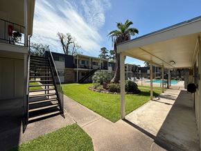 Beaumont apartment for rent - A sunny day at a residential complex with a pool and palm trees.