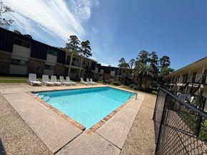 Beaumont apartment for rent - A swimming pool surrounded by a black fence and chairs.