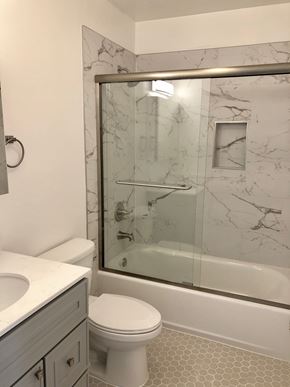Oakland apartment for rent - A white toilet sits next to a sink in a marble bathroom.