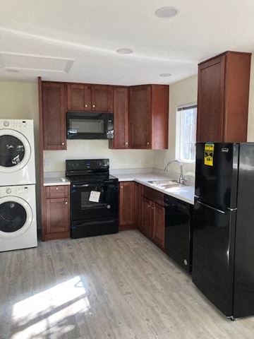 Alameda apartment for rent - A black refrigerator is in a kitchen with wooden cabinets.