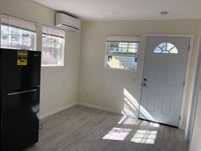 Alameda apartment for rent - A room with a black fridge, a window with blinds, a door and a wall with a window.