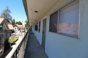 Alameda apartment for rent - A long white building with a balcony and a green door.