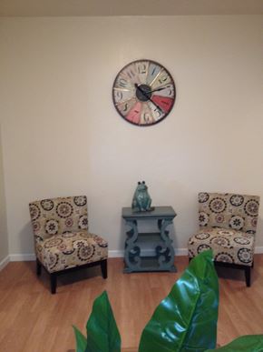Alameda apartment for rent - A wall clock hangs above a table with two chairs and a vase on it.