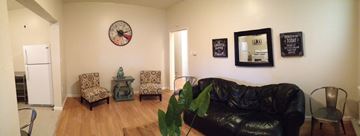Alameda apartment for rent - A black leather couch sits in a living room with a clock on the wall.