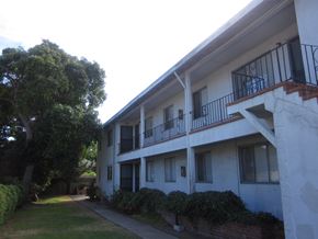 Alameda apartment for rent - A white building with a balcony and a tree in front of it.