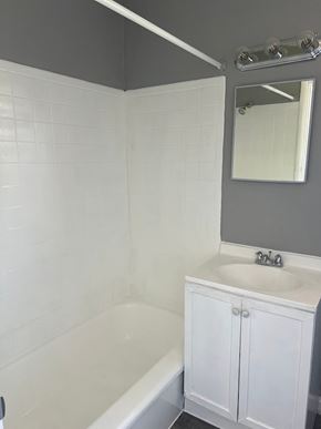 Cincinnati apartment for rent - A white bathroom with a white tub, sink, and a mirror.