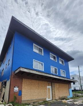 Cincinnati apartment for rent - A blue building with a white door and windows is boarded up.