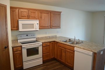 Mandan apartment for rent - a kitchen with white appliances and wooden cabinets