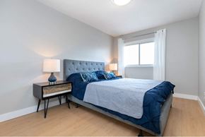 Toronto apartment for rent - A bedroom with a bed, nightstand, and lamp.
