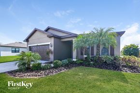 Parrish house for rent - a house with a lawn and palm trees in front of it