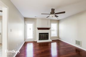 Charlotte house for rent - an empty living room with a fireplace and a ceiling fan