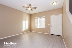 Surprise house for rent - an empty living room with a ceiling fan and a white door