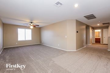 Surprise house for rent - a spacious living room with carpet and a ceiling fan