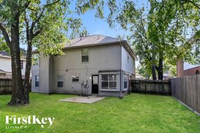 Humble house for rent - the back of a white house with a yard and trees