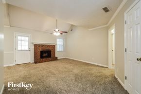 Conyers house for rent - an empty living room with a fireplace and a ceiling fan