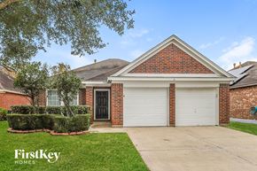 Humble house for rent - A brick house with a black door and a garage door.