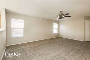 Denton house for rent - A spacious room with a ceiling fan and two windows.