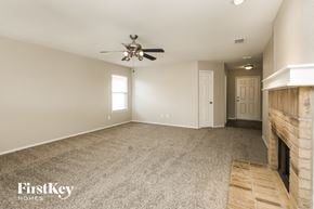 Denton house for rent - A spacious room with a fireplace and a ceiling fan.