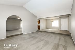 Glendale house for rent - A spacious room with a carpeted floor and a chandelier hanging from the ceiling.