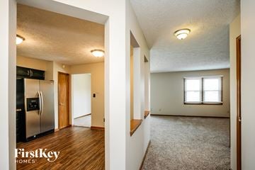 Indianapolis house for rent - A kitchen with a refrigerator and a living room with a window.