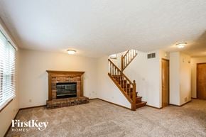 Indianapolis house for rent - A spacious living room with a fireplace and a staircase.