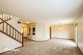 Indianapolis house for rent - A spacious living room with a staircase on the left side and a chandelier hanging from the ceiling.