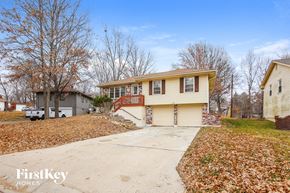 Kansas City house for rent - a yellow house with a driveway and a garage door