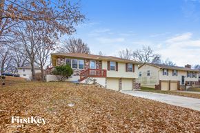 Kansas City house for rent - the front of a yellow house with a yard with fallen leaves