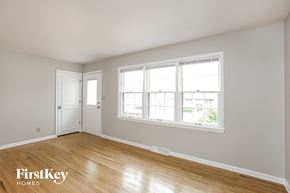 Kansas City house for rent - a bedroom with a hardwood floor and three windows and a door