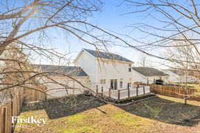 O'fallon house for rent - A house with a white exterior and a black roof is surrounded by a wooden fence and leafless trees.