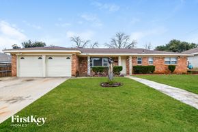 Fort Worth house for rent - A brick house with a white garage door and a green lawn.