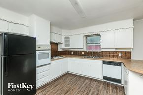 Fort Worth house for rent - A kitchen with white cabinets and a black fridge.